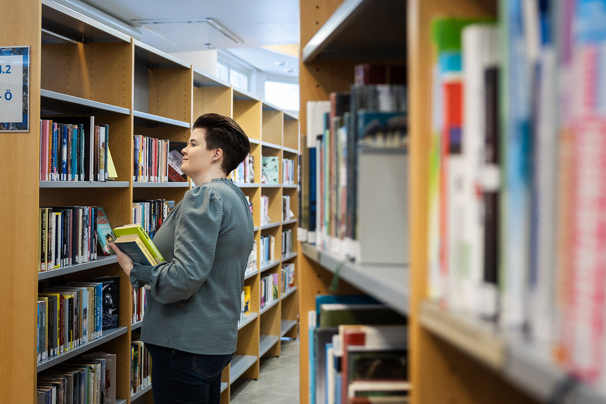 Lukutaitovalmentaja etsimässä sopivaa kirjallisuutta aikuisille.